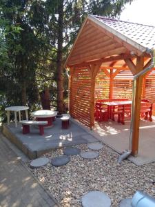 a wooden pavilion with a picnic table and benches at Gesztenyes Vendeghaz in Bükkszék