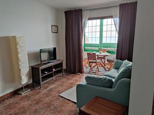 salon z kanapą, telewizorem i stołem w obiekcie Apartamento Vista al Mar w mieście Los Silos