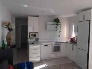 Biała kuchnia z białymi szafkami i urządzeniami w obiekcie Arroyo mar & montaña cozy place w mieście Benalmádena