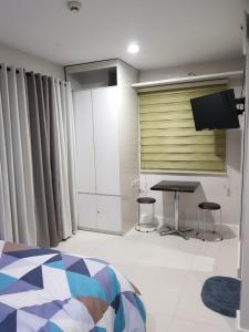 um quarto com uma cama, uma mesa e uma televisão em Skymagz 812 at Cityscape Residences em Bacolod