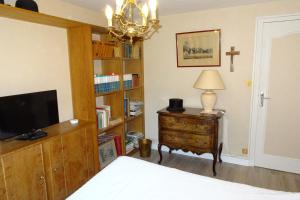 a bedroom with a bed and a dresser with a television at Chambres d'Hôtes à la Fontanille in Panazol