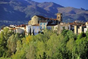 un gruppo di edifici su una collina con montagne sullo sfondo di Le jardin des pensées a Le Boulou