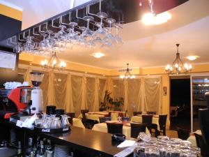 a restaurant with a bar with chandeliers and tables at ADMAR Rooms & Restaurant in Costinesti