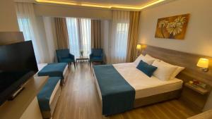 チャナッカレにあるPelit Troya Hotelのベッド1台、薄型テレビが備わるホテルルームです。