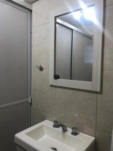 y baño con lavabo, espejo y ducha. en Apartamentos Don Bosco en Paso de los Libres