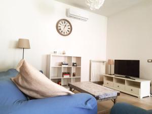 a living room with a blue couch and a clock on the wall at Casa di Nicola in Viareggio