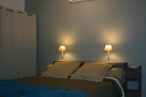 a bedroom with a bed with two lamps on the wall at Gîte Le Balthazar in Mercurey