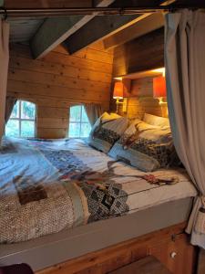 ein Schlafzimmer mit einem Bett in einem Blockhaus in der Unterkunft Het Swadde huisje in Twijzelerheide