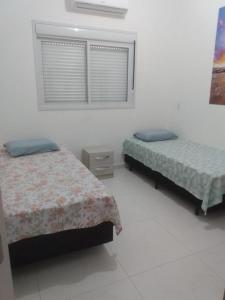 een slaapkamer met 2 bedden en een raam bij Ap 203 - Mônaco Residence - rua na Beira da Praia - Não aceita pet in Florianópolis