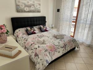 a bedroom with a bed with a floral comforter at AGM Suite Rome Airport FCO - Attico Parco Leonardo in Fiumicino