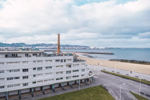 un edificio blanco junto a una playa y un edificio en EL SEXTO DE LA PLAYA + PARKING GRATIS en Gijón