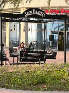 a woman sitting on a bench in front of a restaurant at BEAUTIFUL STUDIO APARTMENT IN AL MARJAN ISLAND in Ras al Khaimah