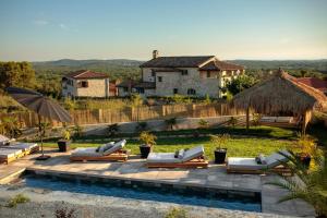 einen Pool mit Liegen und Sonnenschirmen neben einem Haus in der Unterkunft Villa Merapi in Sveti Lovreč Pazenatički