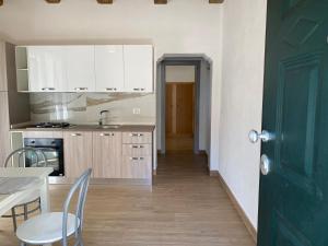 una cucina con armadi bianchi e una porta verde di Appartamento da Antonio a Parghelia
