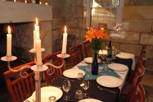 Fitzroy Inn Historic Retreat Mittagong في ميتاغونغ: طاولة عليها الشموع والصحون والزهور