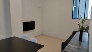 ein Wohnzimmer mit einem Tisch und einem TV in der Unterkunft Appartement 7 - T3 70m2 - Standing, moderne et tout équipé - Carmes-Renforts , Toulouse in Toulouse