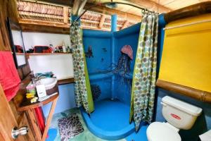 a blue bathroom with a toilet and shower curtains at Maracumbo Lodge in Mompiche