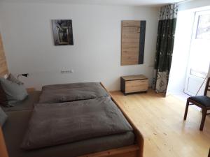 een slaapkamer met een bed, een stoel en een raam bij Achtalgarten in Pfronten