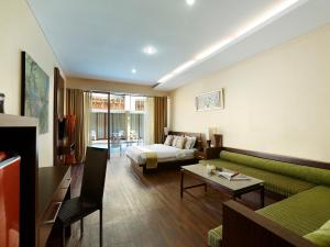a living room with a couch and a bed at Devata Suites and Residence in Legian