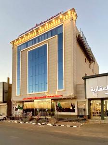 a large building with lights on the side of it at Aral Hotel Apartments in Tabuk