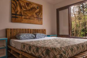 a bedroom with a bed and a large window at The Eco Palace Hostel in Búzios