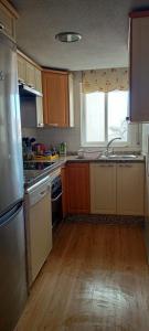 a kitchen with wooden floors and a stainless steel refrigerator at EL DESVÁN in Santa Marta de Tormes