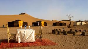 un tavolo in mezzo al deserto con tende di Atta Desert Camp a El Gouera
