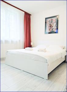 ein weißes Bett in einem Schlafzimmer mit einem roten Vorhang in der Unterkunft Smart Apartament in Piatra Neamţ
