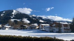 uma aldeia coberta de neve com uma montanha ao fundo em Bergblick em Westendorf