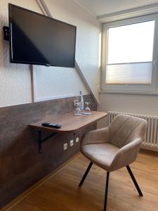 a room with a chair and a television on a wall at Hotel Schütz in Trier