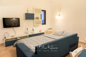 The Blue House, Pedras D'el Rei, Tavira في تافيرا: غرفة نوم مع سرير وتلفزيون على الحائط