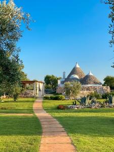 a walkway in a park with huts in the background at I Trulli di Alice in Ceglie Messapica