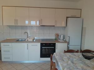 a kitchen with white cabinets and a sink and a table at Apartments Donadic I, Caska in Novalja