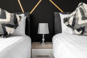two beds with white sheets and a lamp on a night stand at City Centre Studio 4 with Kitchenette, Free Wifi and Smart TV by Yoko Property in Middlesbrough