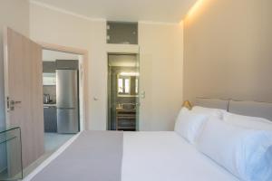 a bedroom with a white bed and a kitchen at Apollonian Luxury Apartments in Vasiliki