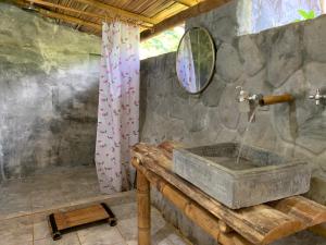 Baño de piedra con lavabo y espejo en Ecohotel Los Mikos, en Norcasia