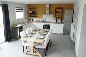 une cuisine avec une table en bois et des chaises blanches dans l'établissement L'Escapade - Maison - Spacieuse - Jardin - Plage, à Zuydcoote