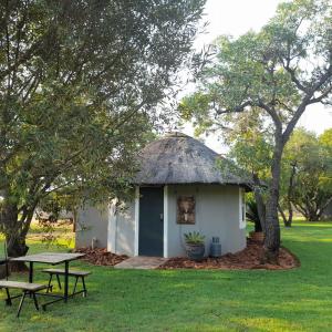 a small hut with a thatched roof and a picnic table at Marico Guest Lodge in Groot-Marico