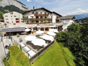 a building with tables and umbrellas in front of it at Arena Lodge in Flims