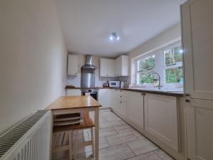 a kitchen with white cabinets and a wooden table at North Cottage in Luss