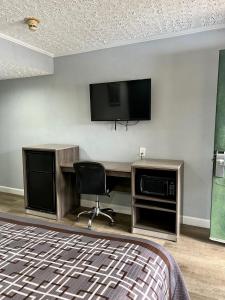 Cette chambre comprend un bureau avec une télévision et une chaise. dans l'établissement Knights Inn Madison Heights, à Madison Heights