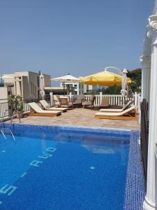 a swimming pool with chairs and umbrellas on a building at Villa Apartmani Anja in Dobra Voda