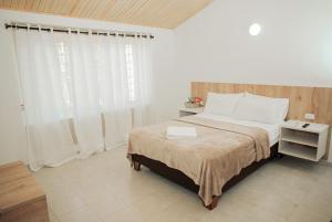 a bedroom with a bed with white sheets and a window at Casa LOURDES in Valledupar