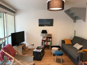 a living room with a couch and a tv at Maison entre forêt et océan - Lacanau Océan in Lacanau-Océan