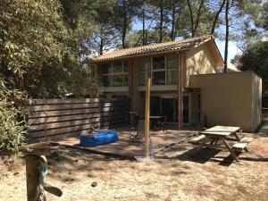 a house with a wooden deck with a picnic table at Maison entre forêt et océan - Lacanau Océan in Lacanau-Océan