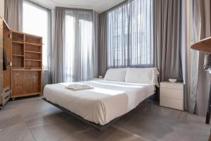 - une chambre avec un grand lit blanc et des fenêtres dans l'établissement BePlace Apartments in Duomo, à Milan