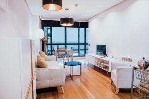 a living room with white furniture and a view of the ocean at PRIMERA LÍNEA PLAYA+PARKING GRATIS in Gijón