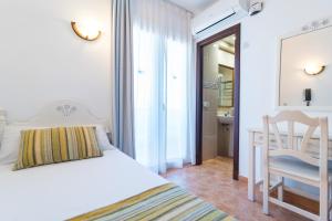 a bedroom with a bed and a desk and a chair at Hotel Ses Puntetes in Cala d´Or