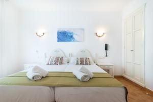 
a bed room with a white bedspread and pillows at Hotel Ses Puntetes in Cala d´Or
