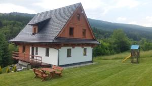 a house with a gambrel roof and a playground at CHALUPA ANNA in Dolní Morava